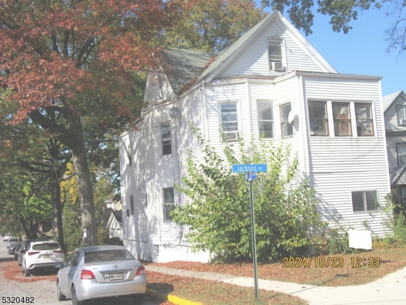 a view of a white house next to a road and trees