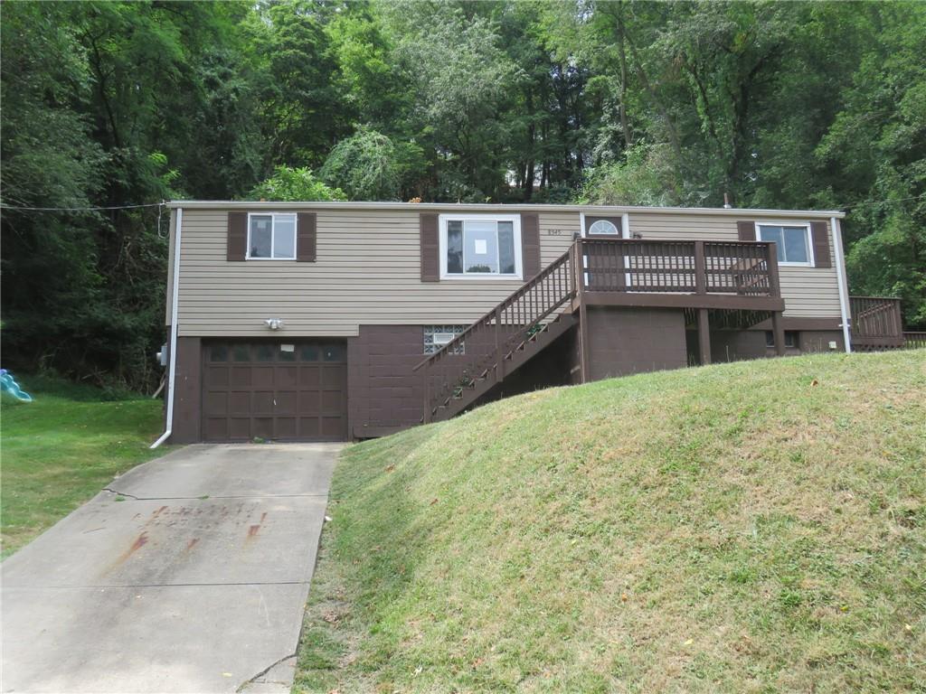 a view of house with backyard and trees in the background