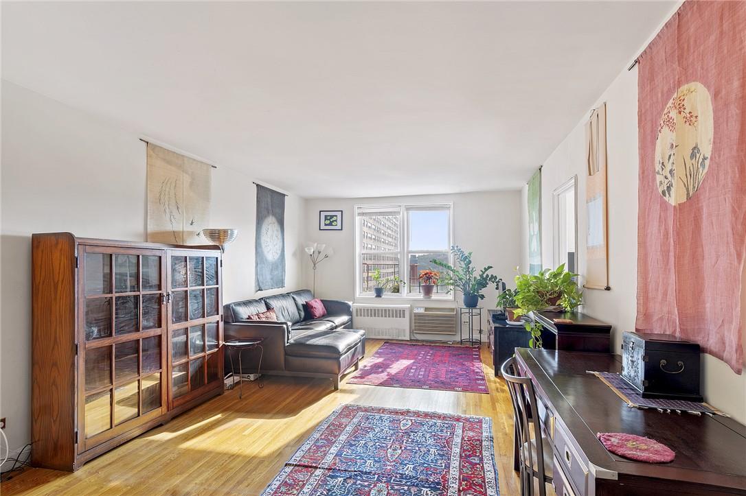 Living room with light hardwood / wood-style floors and radiator heating unit