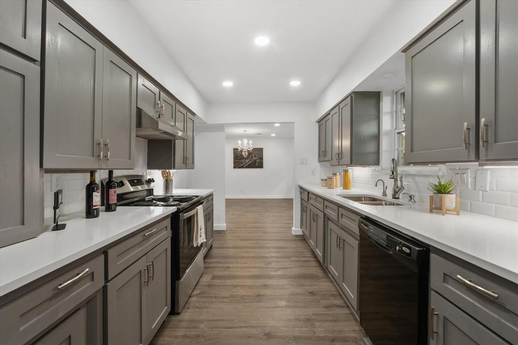 Kitchen with stainless steel stove, tasteful backsplash, hardwood / wood-style floors, black dishwasher, and sink