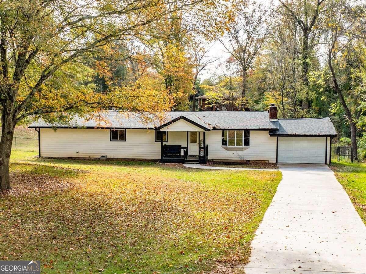 a front view of house with yard and trees in the background