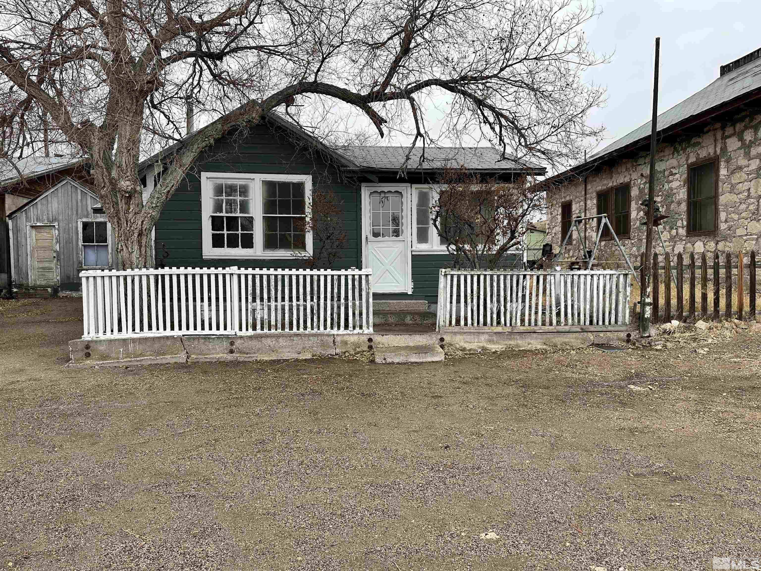 a view of a house with a wooden fence and a large tree