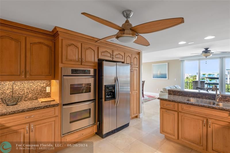 a kitchen with stainless steel appliances granite countertop a refrigerator a oven and white cabinets