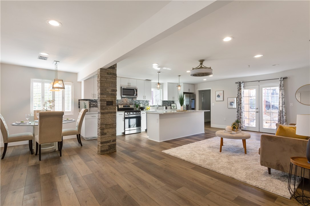 a living room with furniture and kitchen view with wooden floor