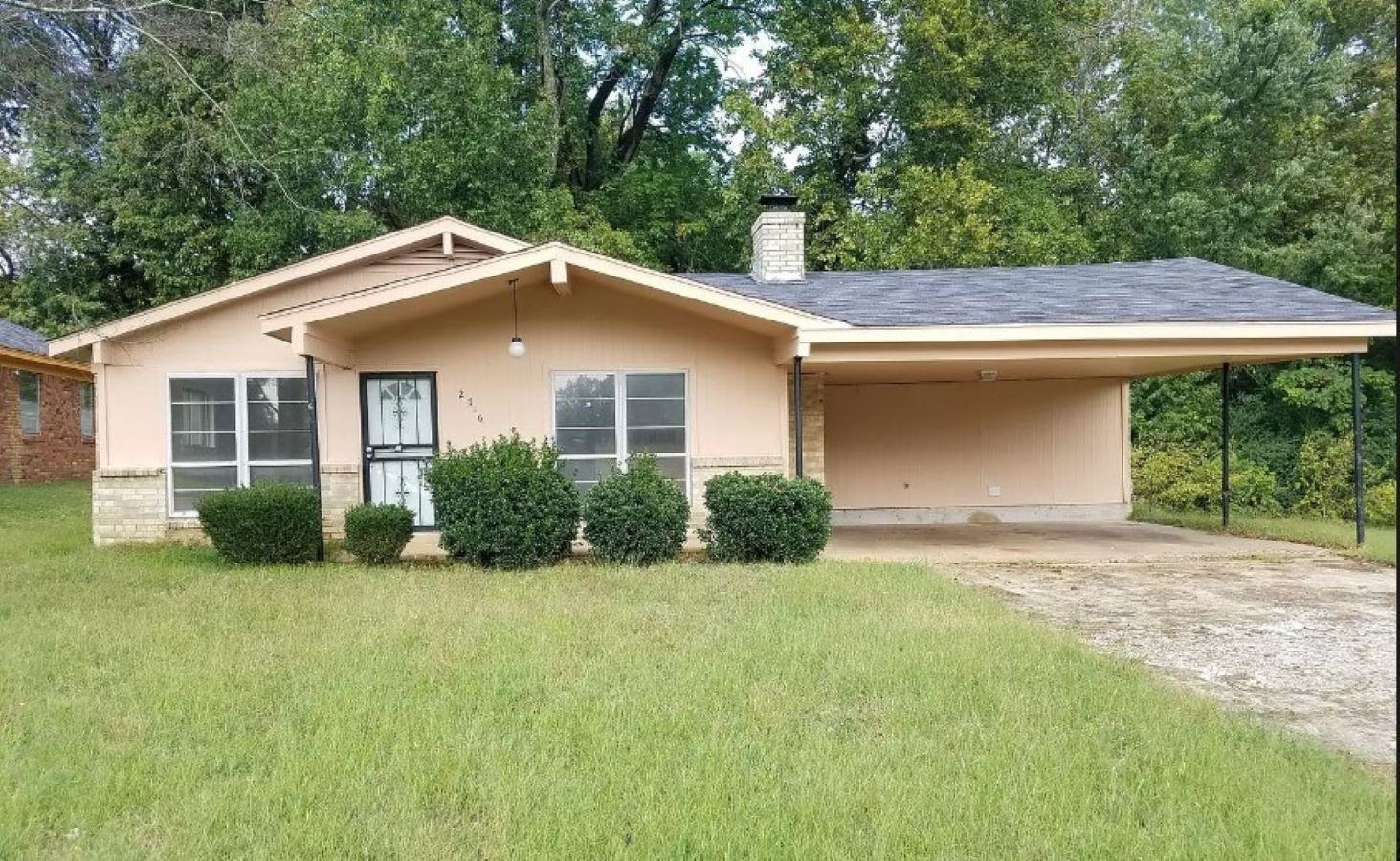 View of front of property with a front yard and a carport