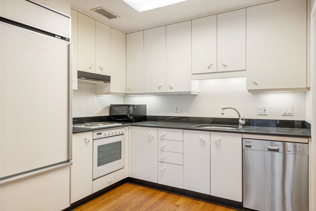 a kitchen with granite countertop white cabinets and white appliances