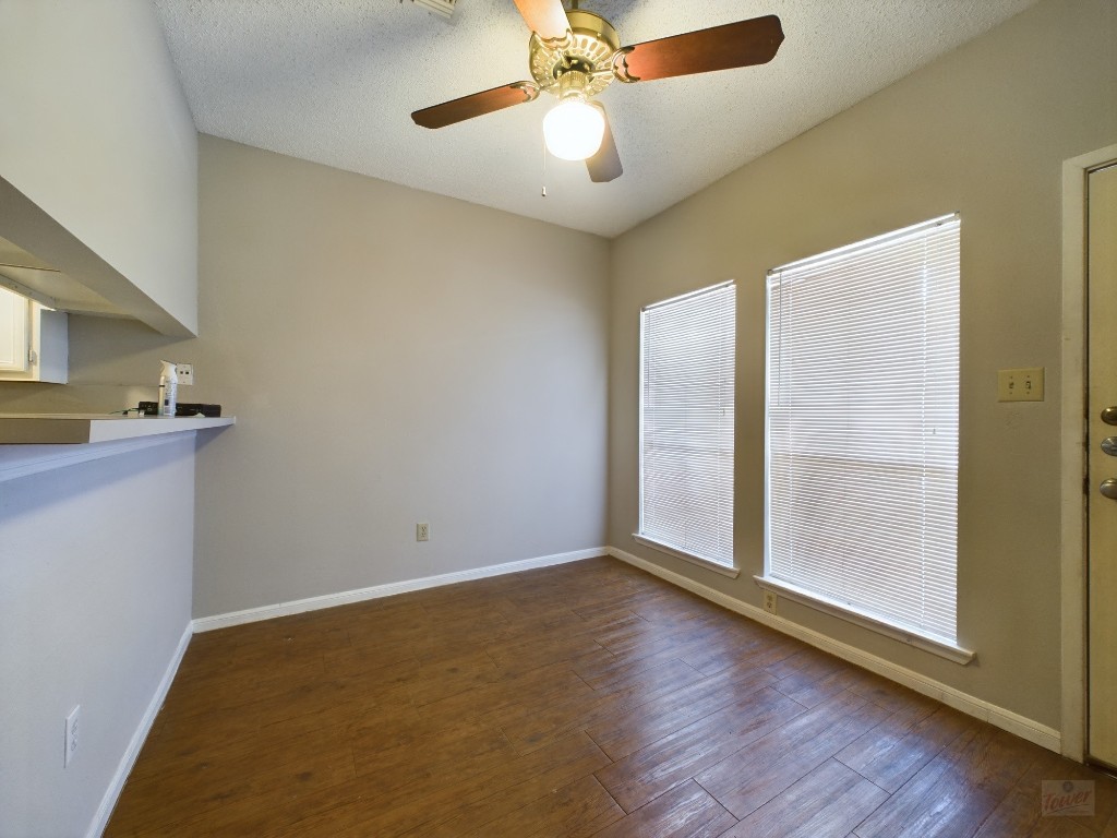 a view of a room with wooden floor and a ceiling fan