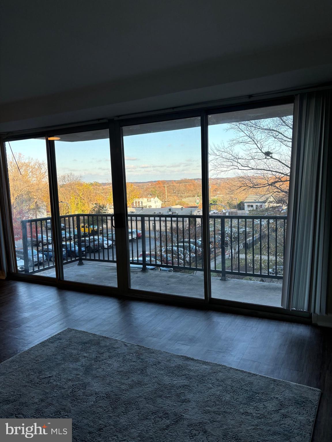 a view of an empty room with wooden floor and a floor to ceiling window