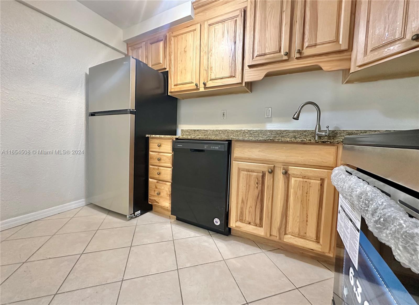 a kitchen with granite countertop a refrigerator and a sink