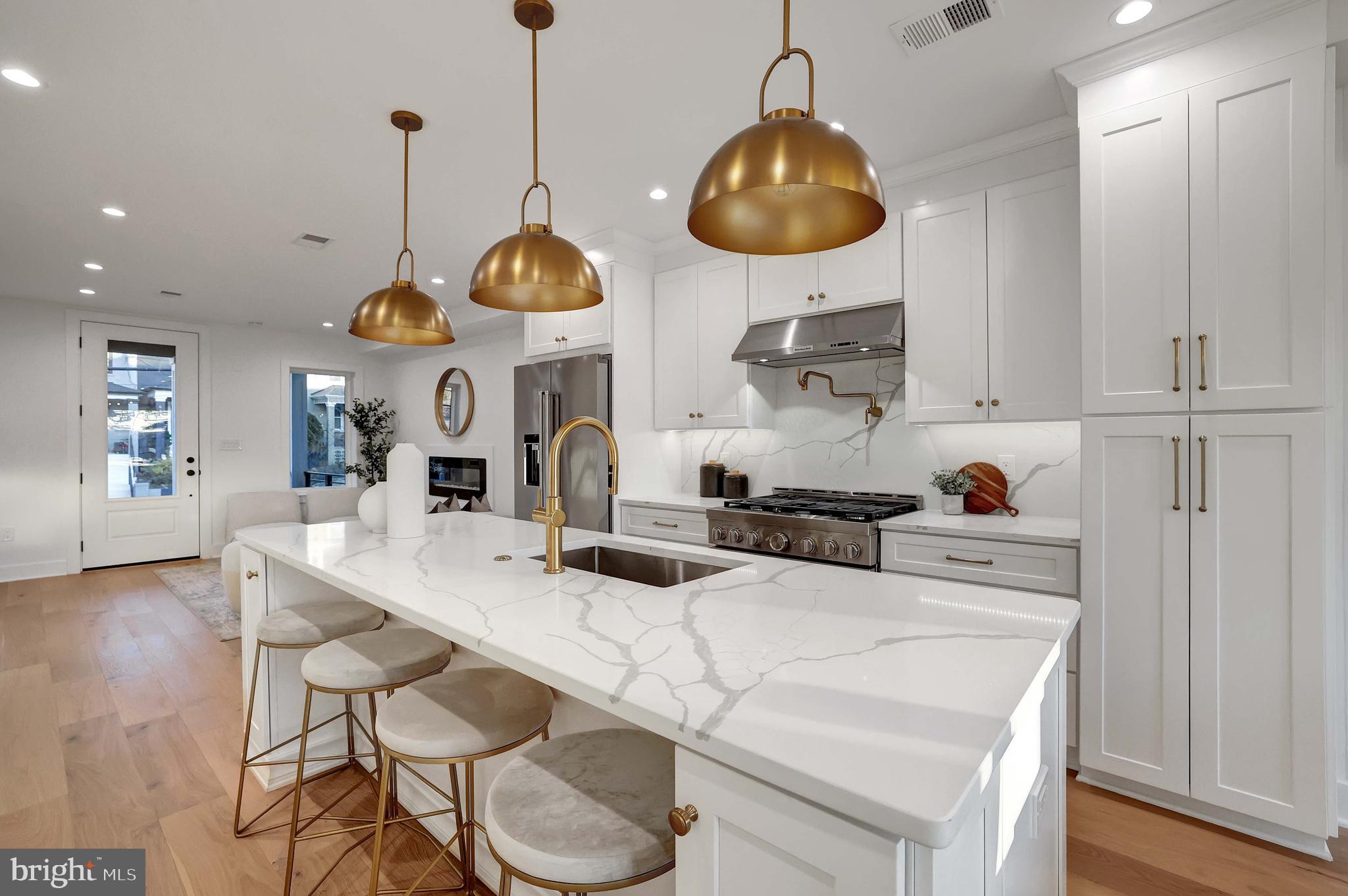 a kitchen with stainless steel appliances a stove a sink and chairs