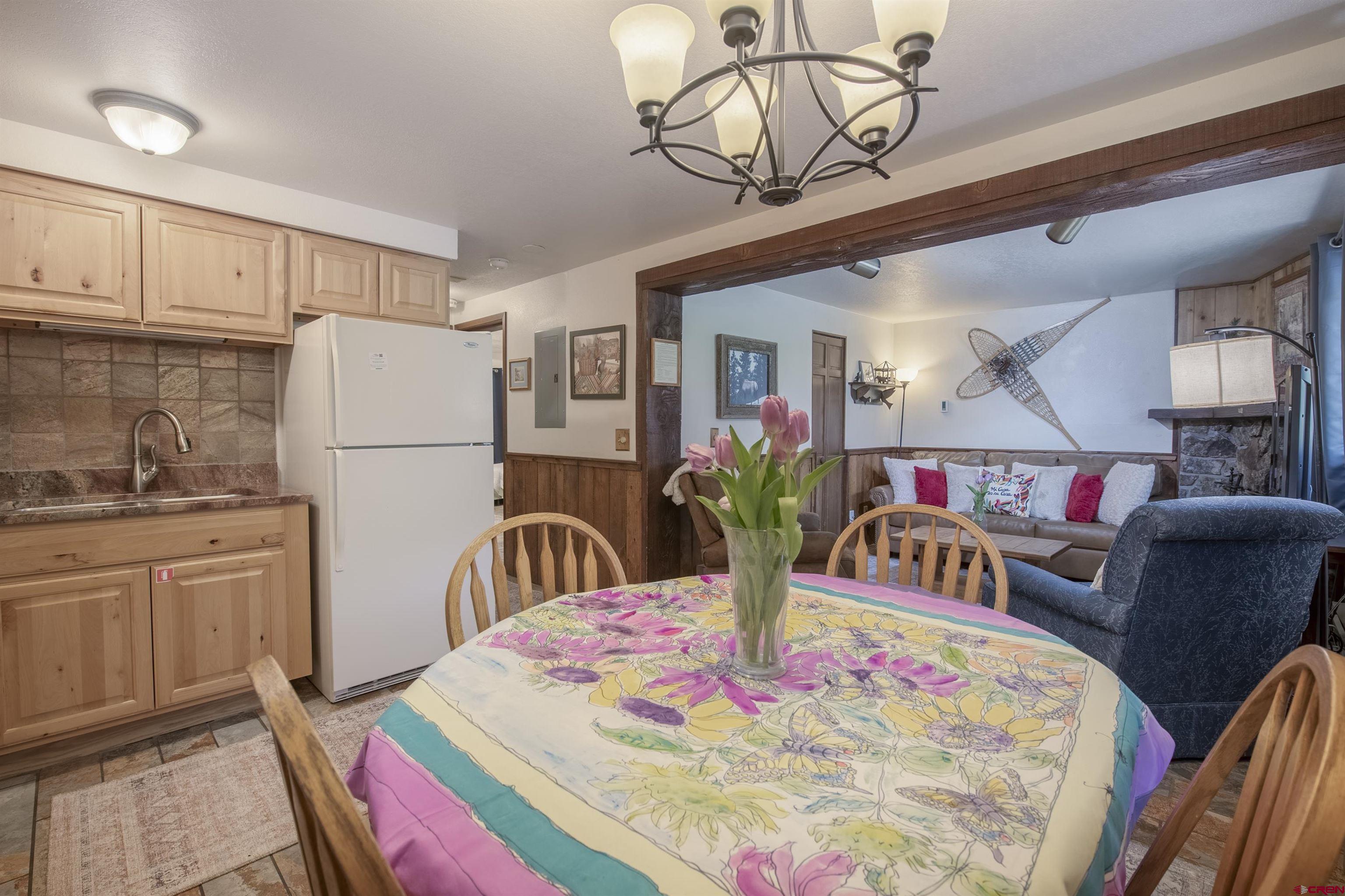 a kitchen with stainless steel appliances granite countertop a dining table chairs and a refrigerator