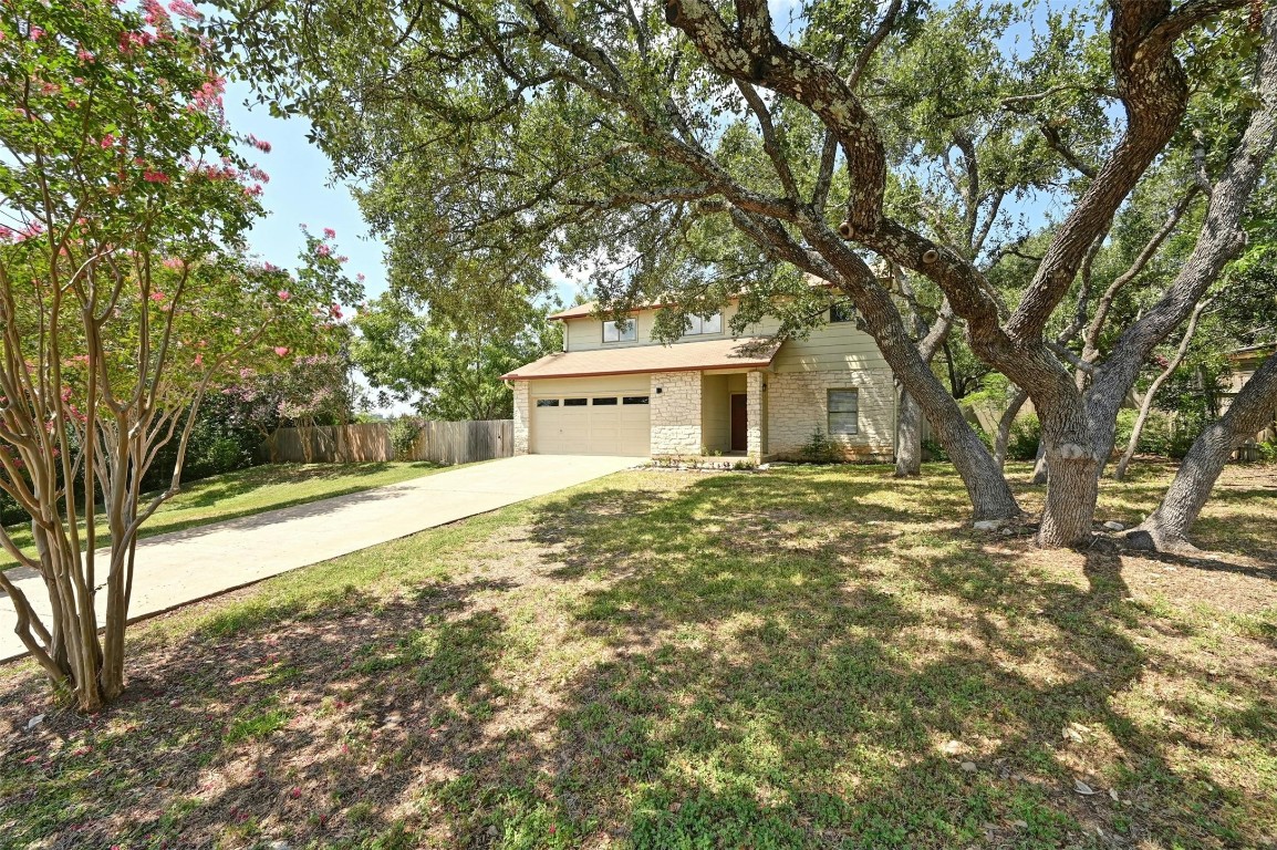 a backyard of a house with large trees and table and chairs