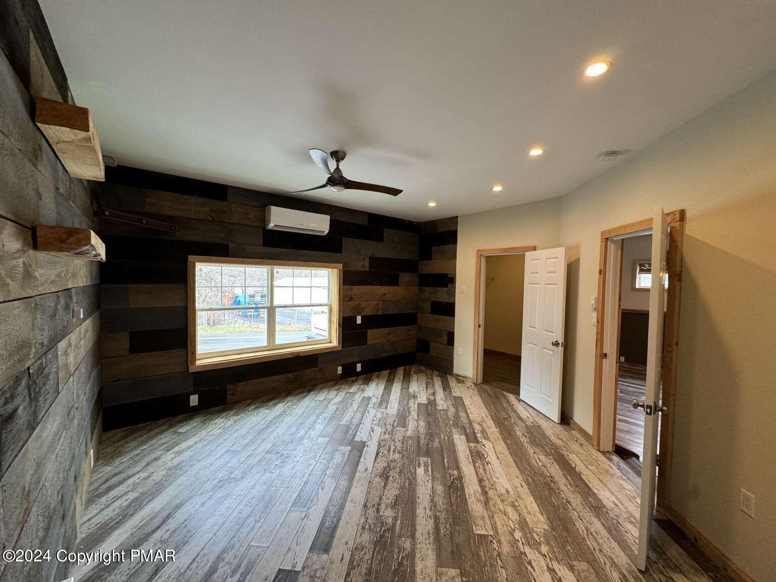 a view of empty room with wooden floor and fan