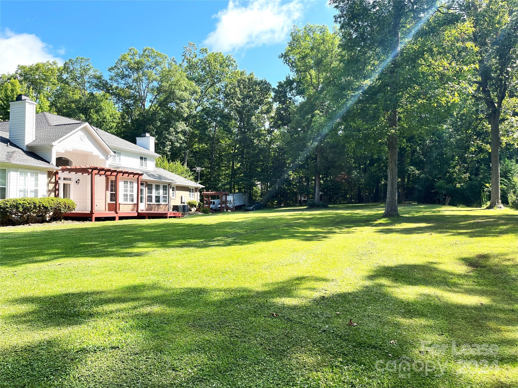 a view of a house with a big yard and large trees