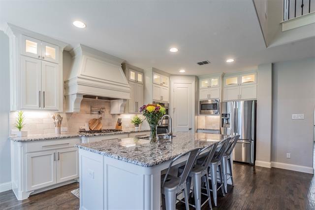 a kitchen with granite countertop kitchen island stainless steel appliances a sink and cabinets