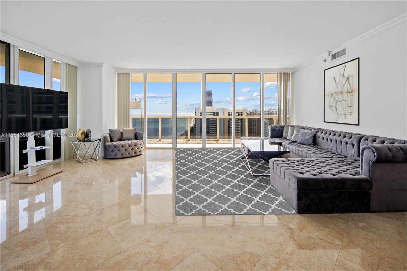 a living room with furniture a flat screen tv and a floor to ceiling window