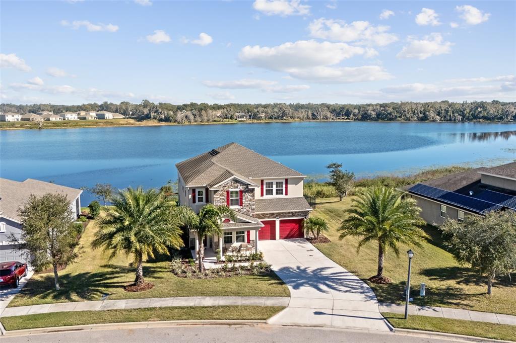 an aerial view of a house with outdoor space and lake view in back