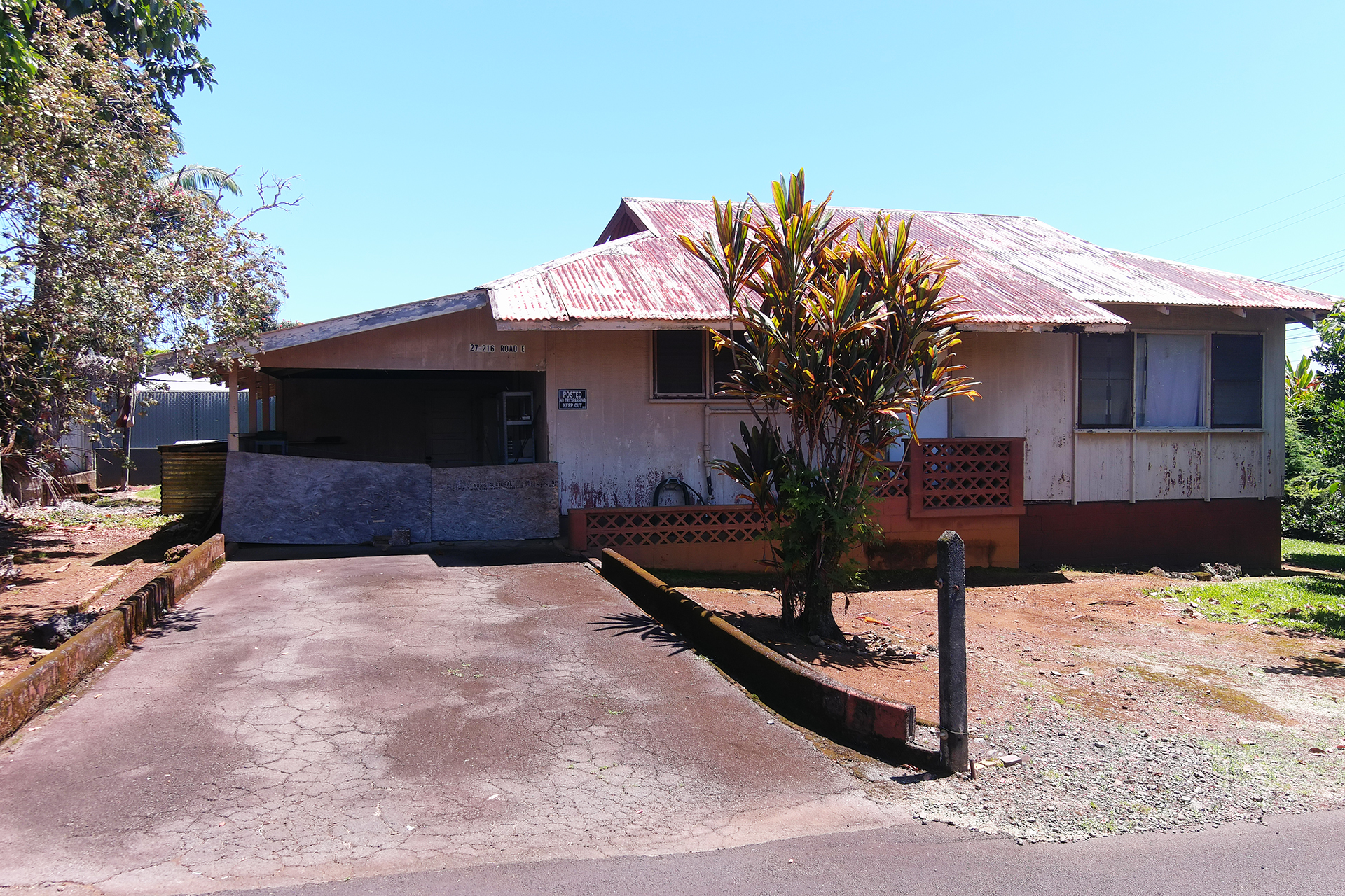 a palm tree sitting in front of a house with wooden fence