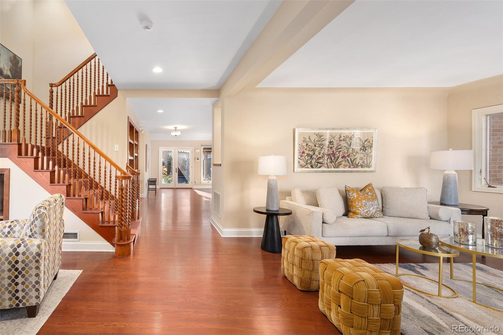 a living room with couches and a dining table with wooden floor