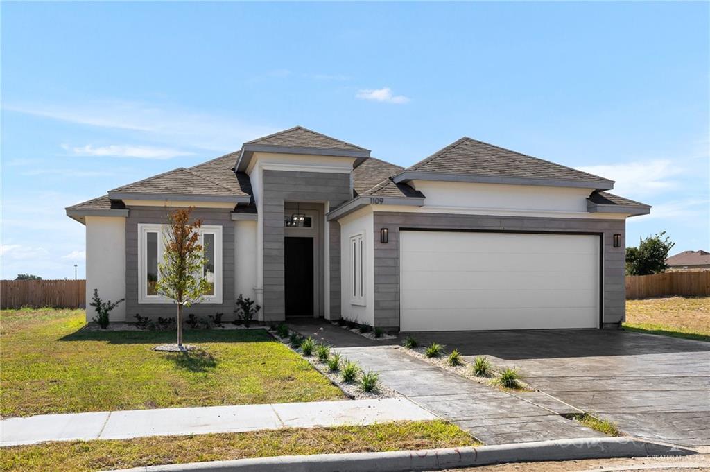 View of front of house with a garage and a front lawn