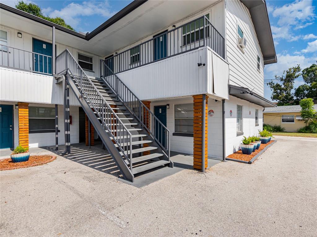 a view of a house with wooden stairs and a car parked in front of house