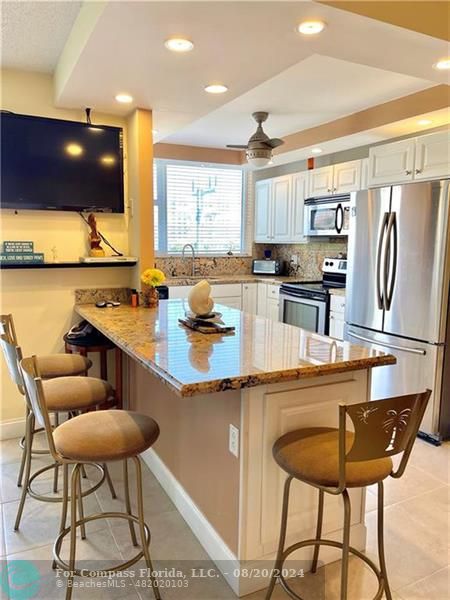 a kitchen with stainless steel appliances granite countertop a sink counter space and chairs in it