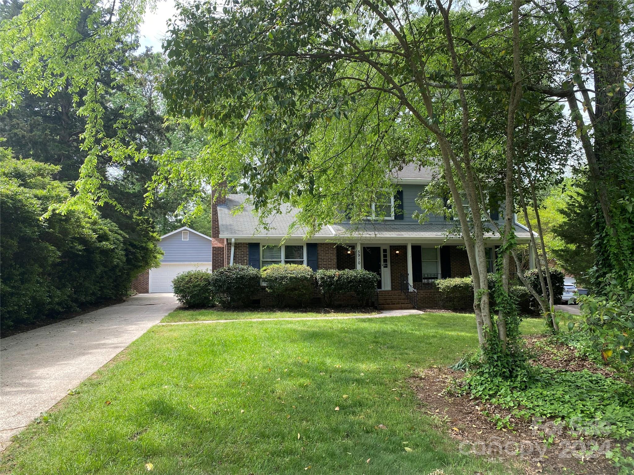 a front view of a house with a garden and trees