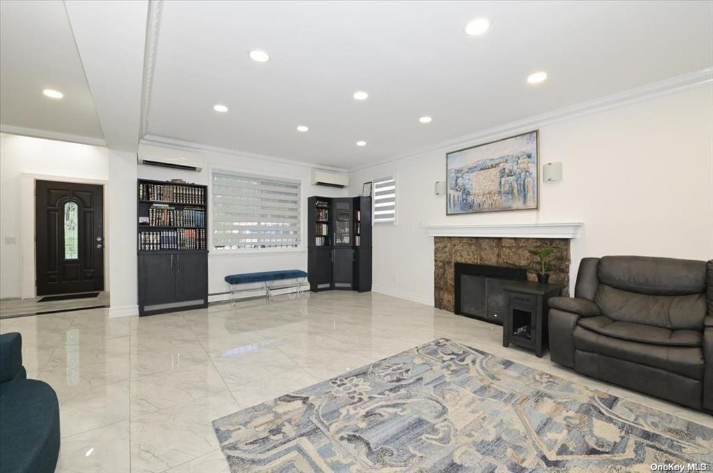 Living room featuring an AC wall unit, a fireplace, and ornamental molding