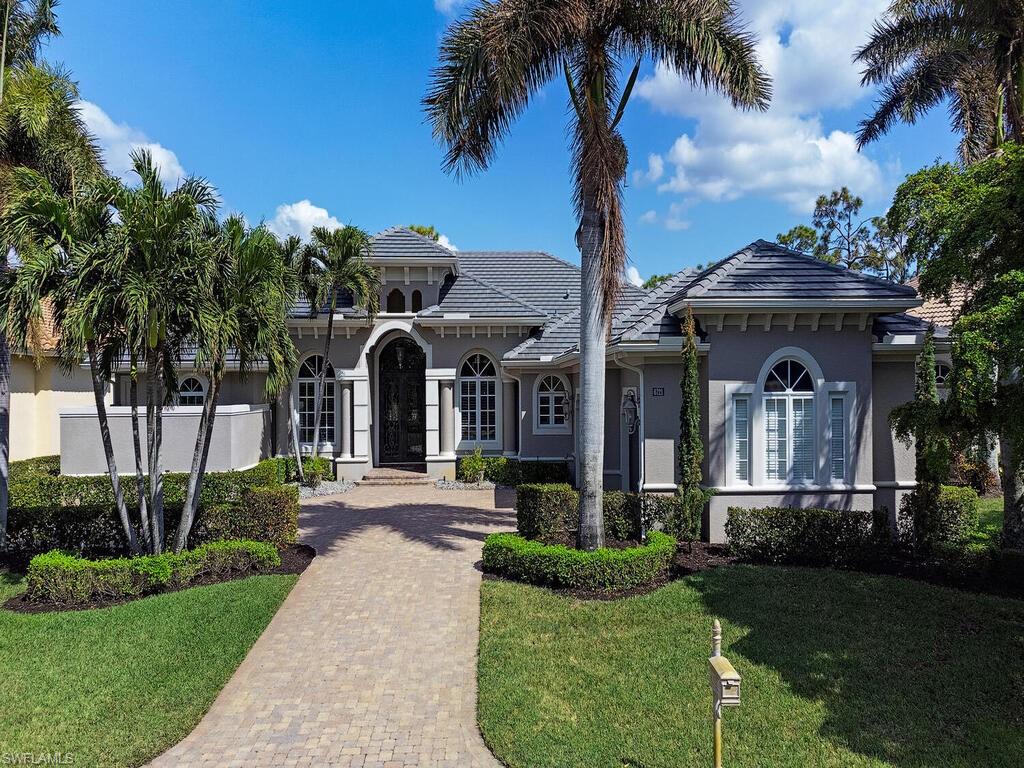 a front view of a house with garden and trees