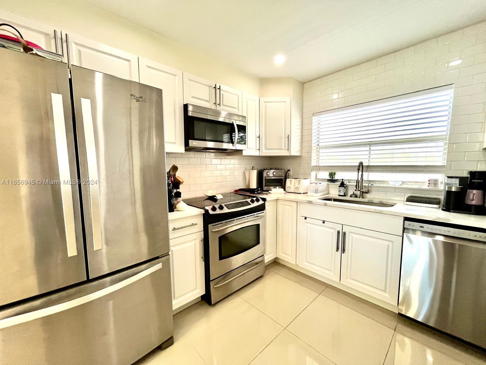 a kitchen with stainless steel appliances a refrigerator sink and microwave