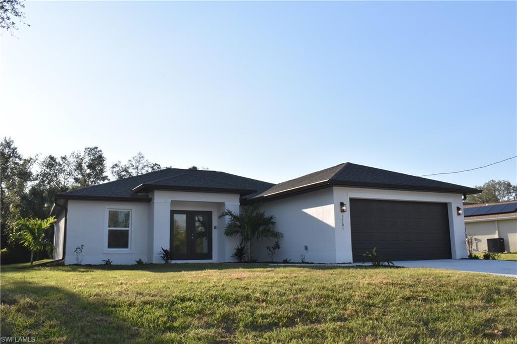 View of front of house featuring french doors, a front lawn, and a garage