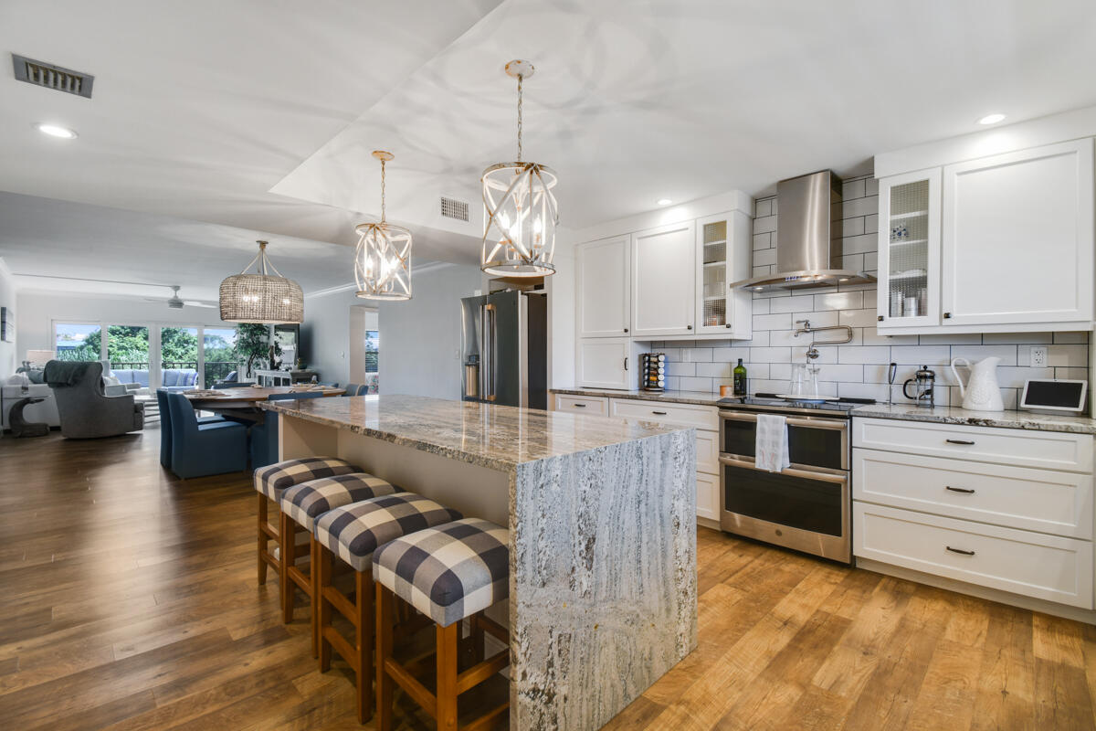 a large kitchen with stainless steel appliances kitchen island granite countertop a stove and a sink