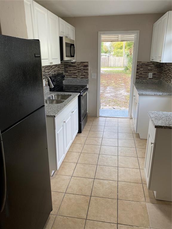 a kitchen with granite countertop a stove a sink and a refrigerator