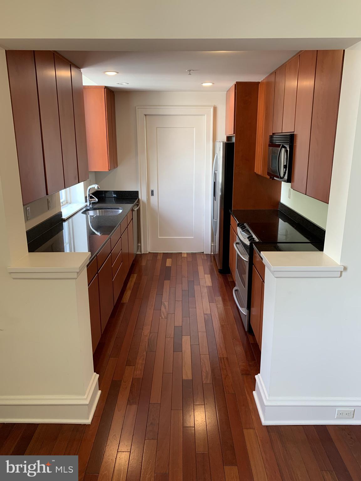 a kitchen with wooden floors and stainless steel appliances