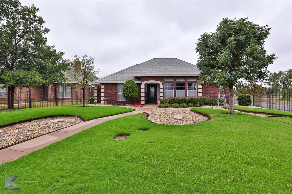 a view of a house with a big yard plants and large trees