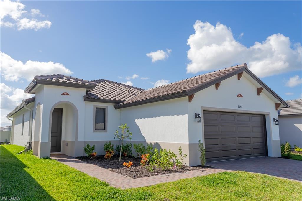 Mediterranean / spanish-style home featuring a garage and a front lawn