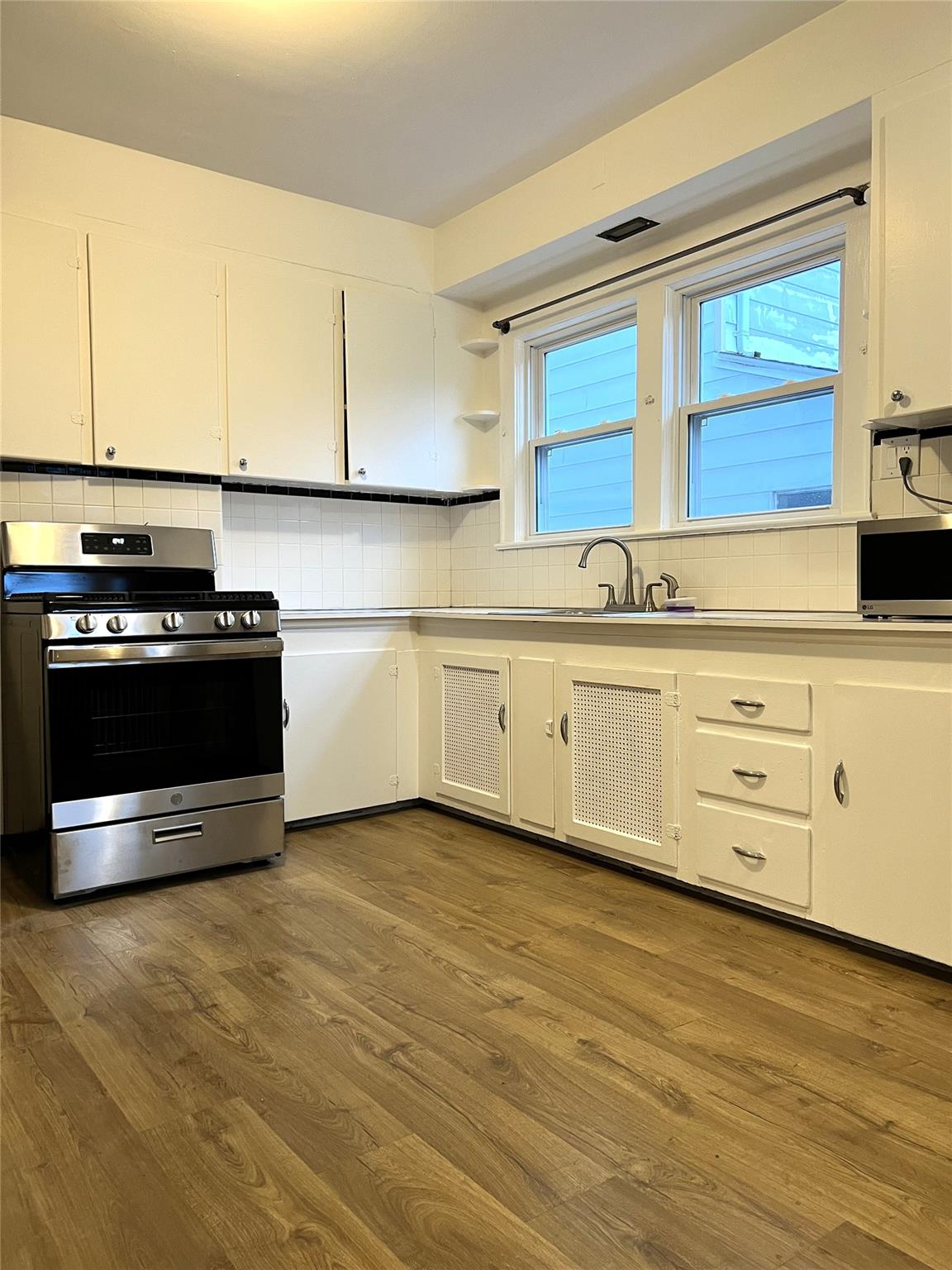 a kitchen with stainless steel appliances granite countertop a stove a sink and white cabinets