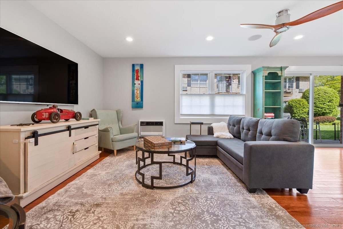 Bright and large living room with hardwood floors, recessed lighting, wired for audio video with smart speakers in the ceiling, with a slider leading to the large patio