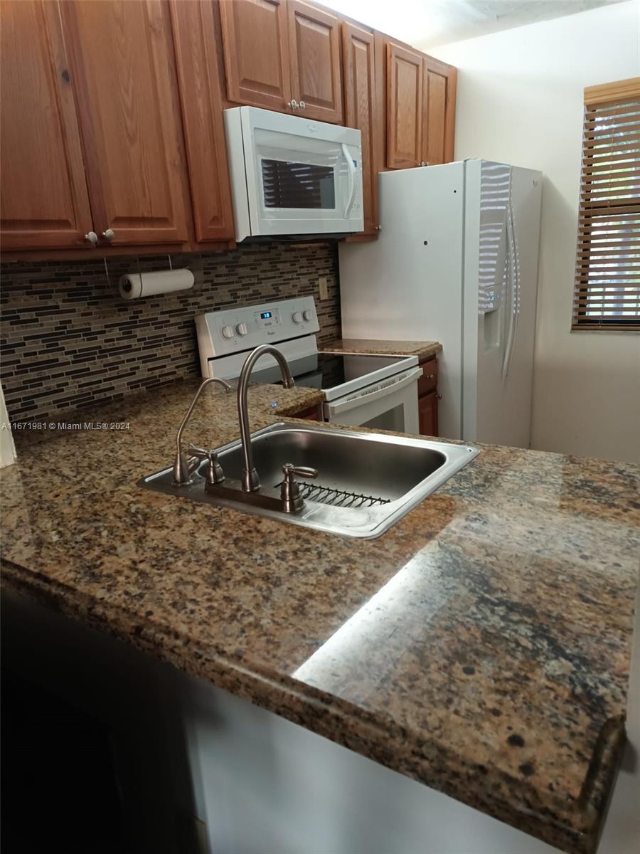 a kitchen with kitchen island granite countertop a sink a stove and a microwave