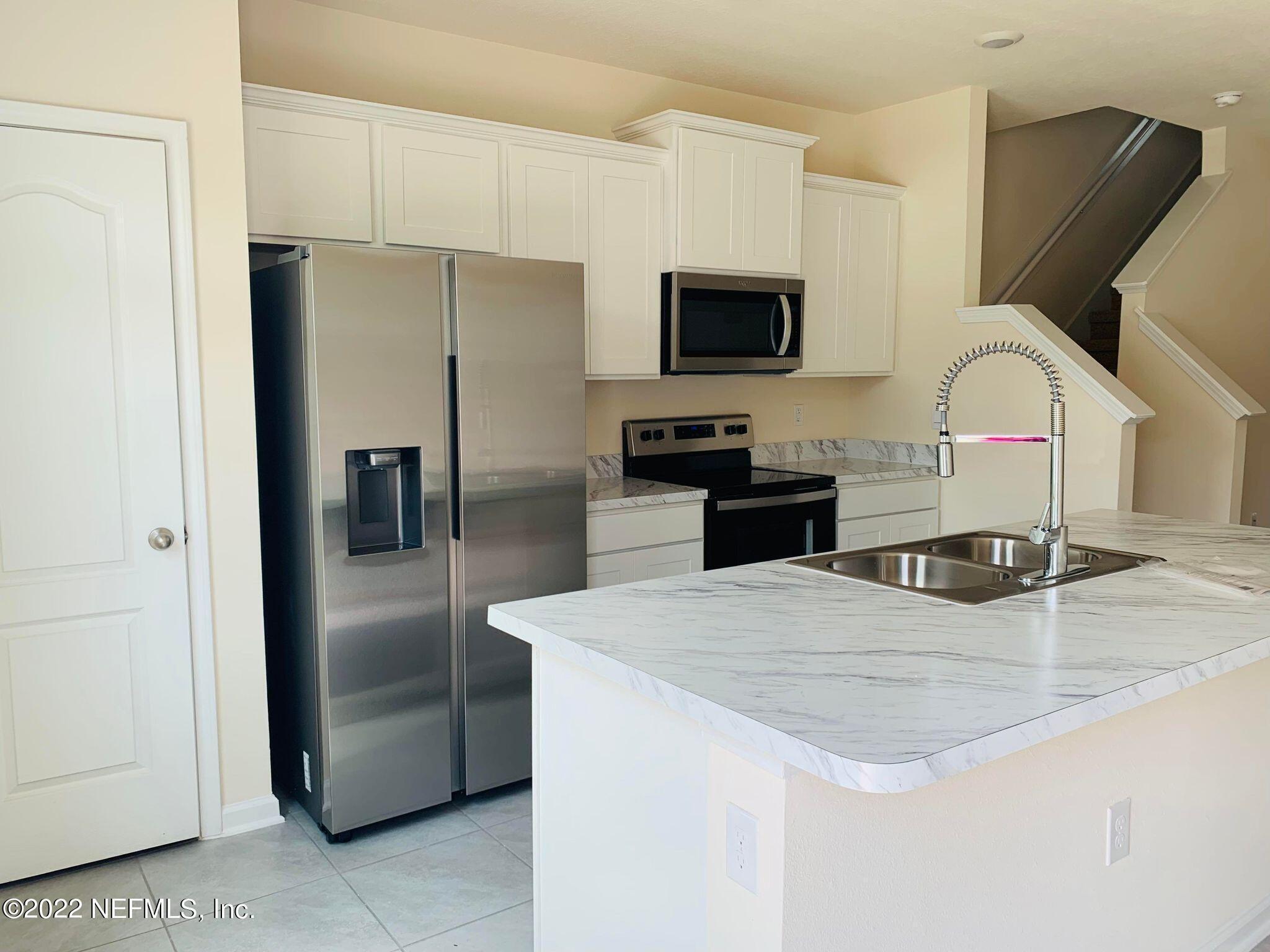 a kitchen with stainless steel appliances kitchen island a refrigerator sink and microwave