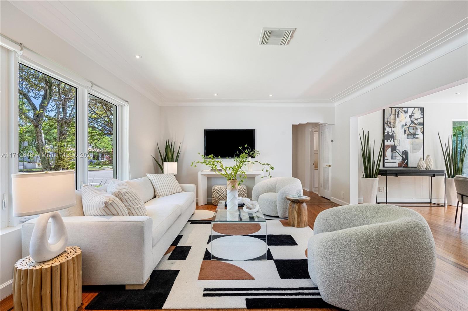 a living room with furniture a flat screen tv and a floor to ceiling window