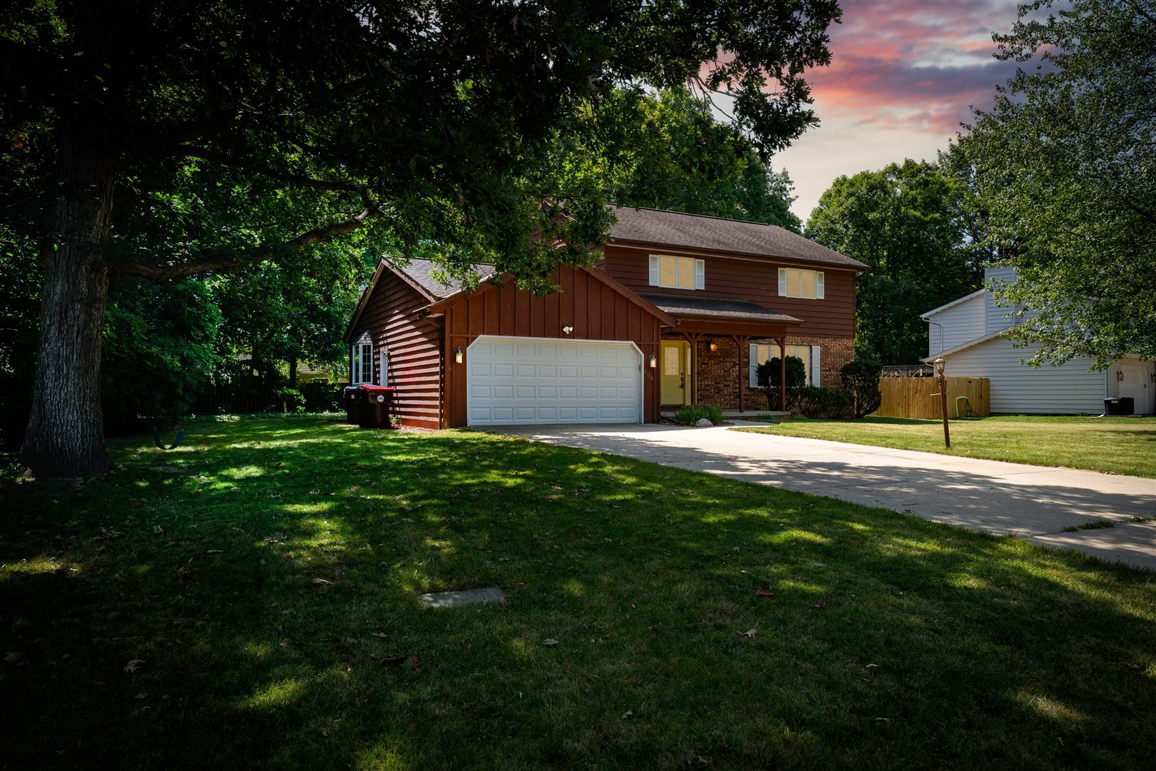 a view of a house with a yard plants and large tree