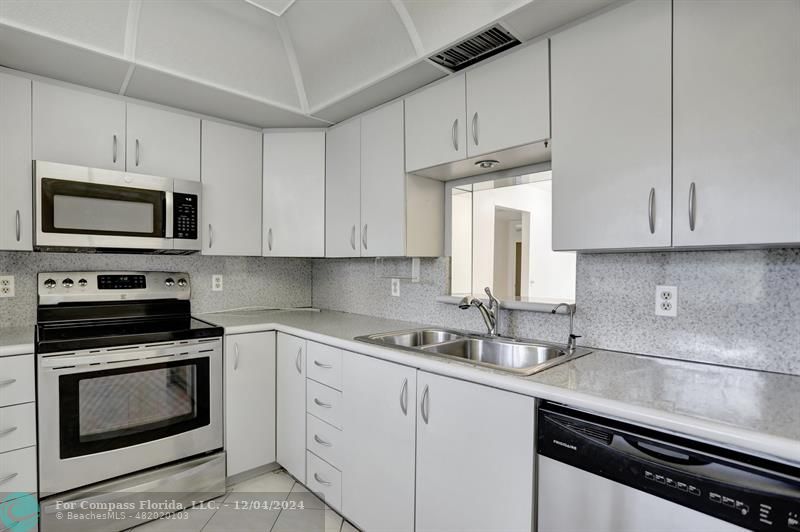 a kitchen with granite countertop white cabinets and stainless steel appliances