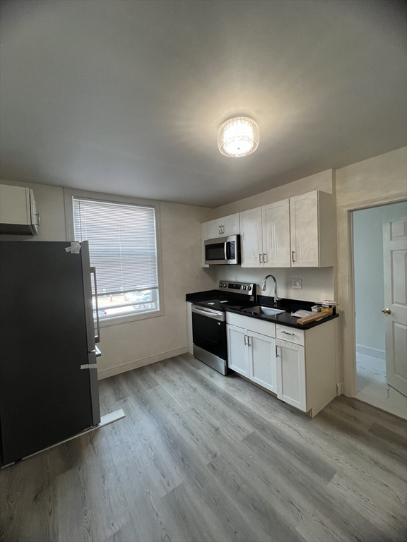 a kitchen with granite countertop a refrigerator and a stove top oven