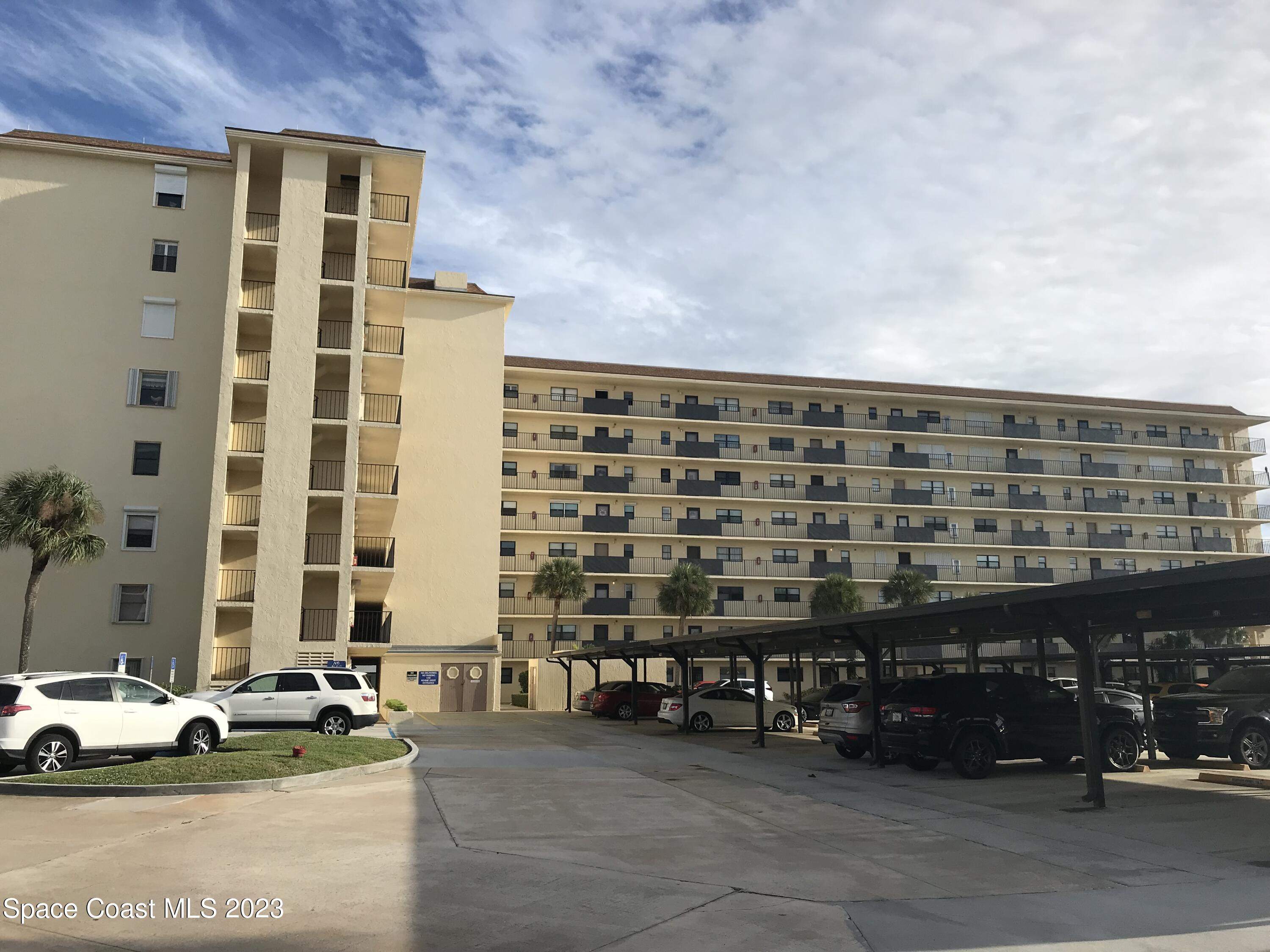 a front view of a building with cars parked