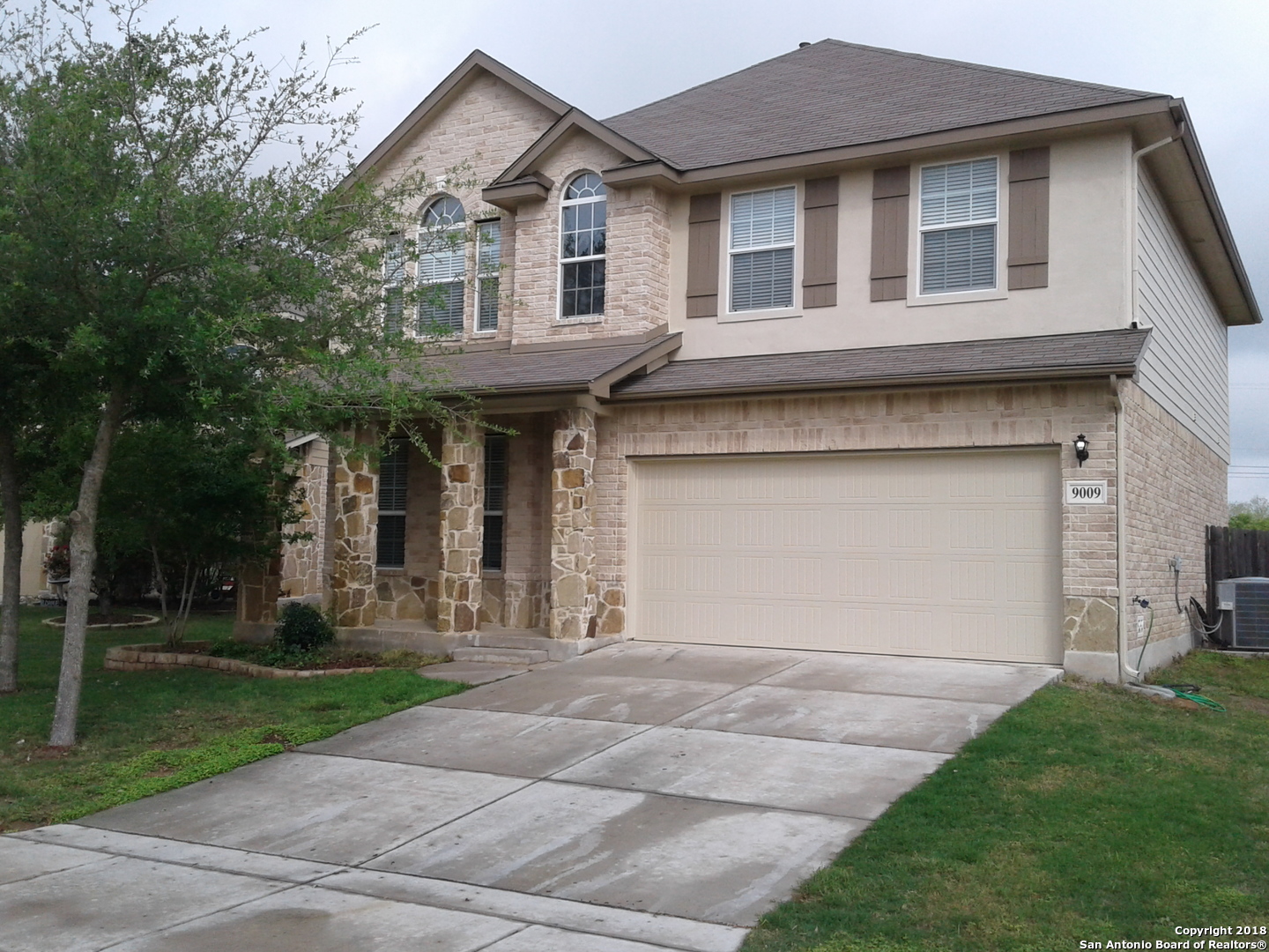 a front view of a house with a garden and trees