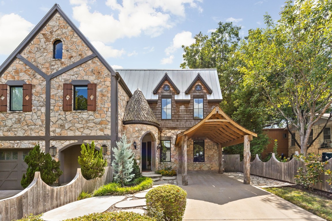 a front view of a house with large trees and plants