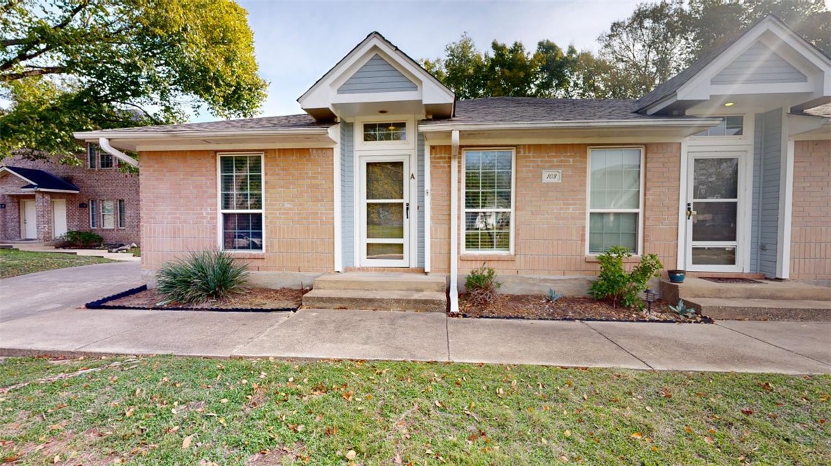 a front view of a house with a yard and potted plants