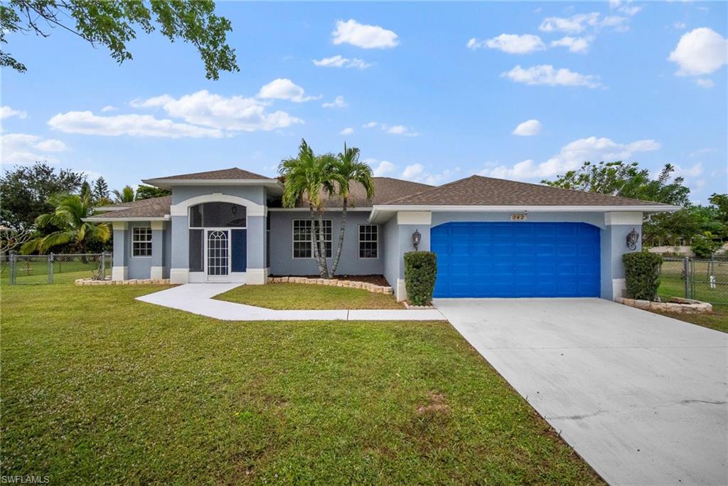 Ranch-style home featuring a garage and a front lawn