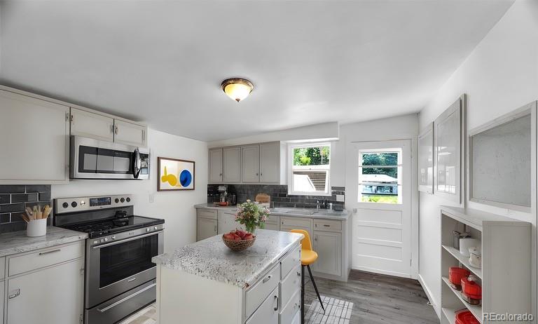 a kitchen with stainless steel appliances granite countertop a stove a sink and a refrigerator